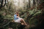 A mother breastfeeds her baby in a lush green forest