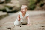 A baby girl crawls along a path and giggles at the camera