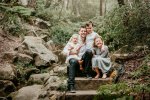 3 children sit with their father sandstone steps in a forrest