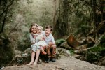 3 little siblings snuggle together in a lush green forest